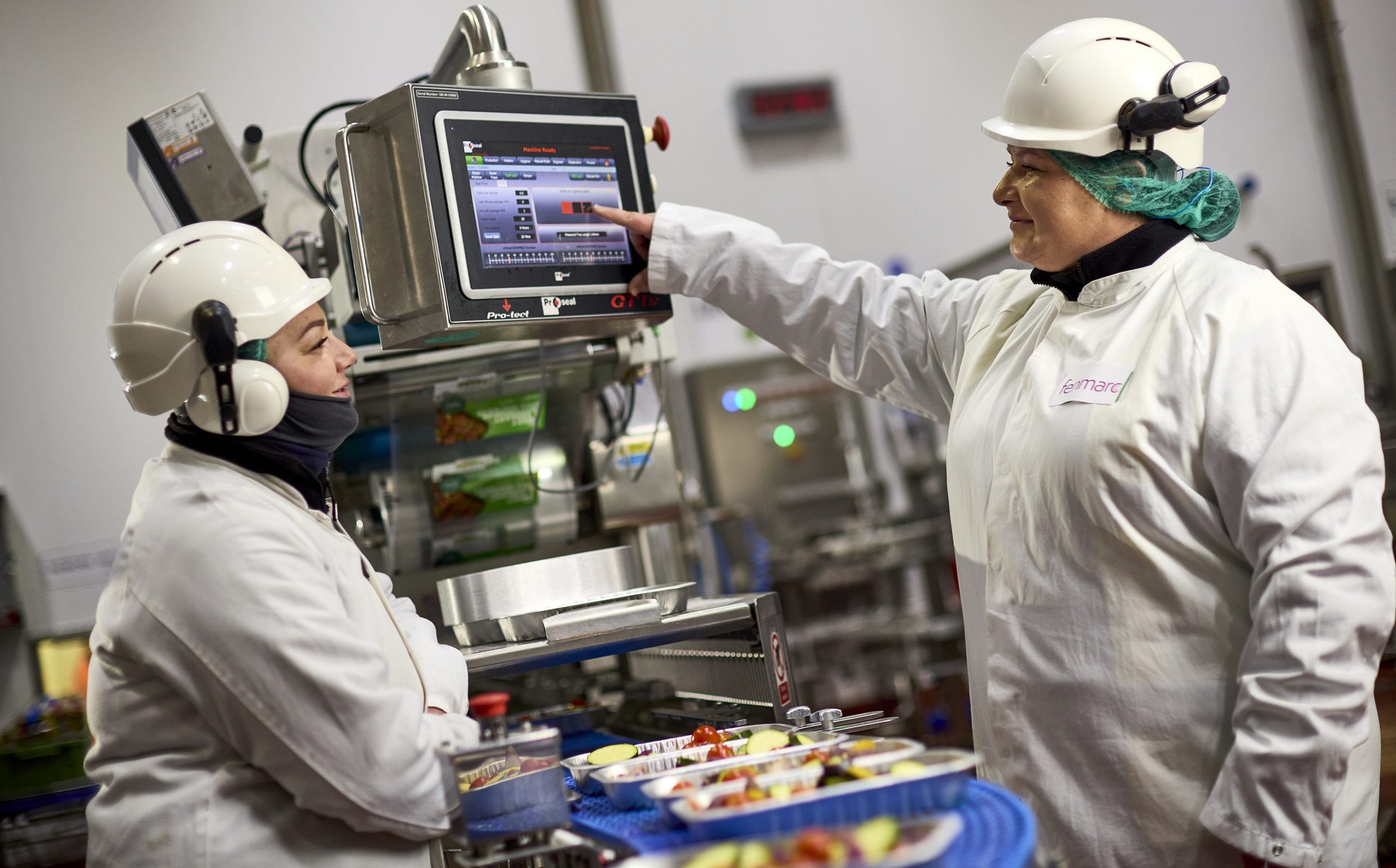 Two fenmarc workers in the warehouse, looking at a screen