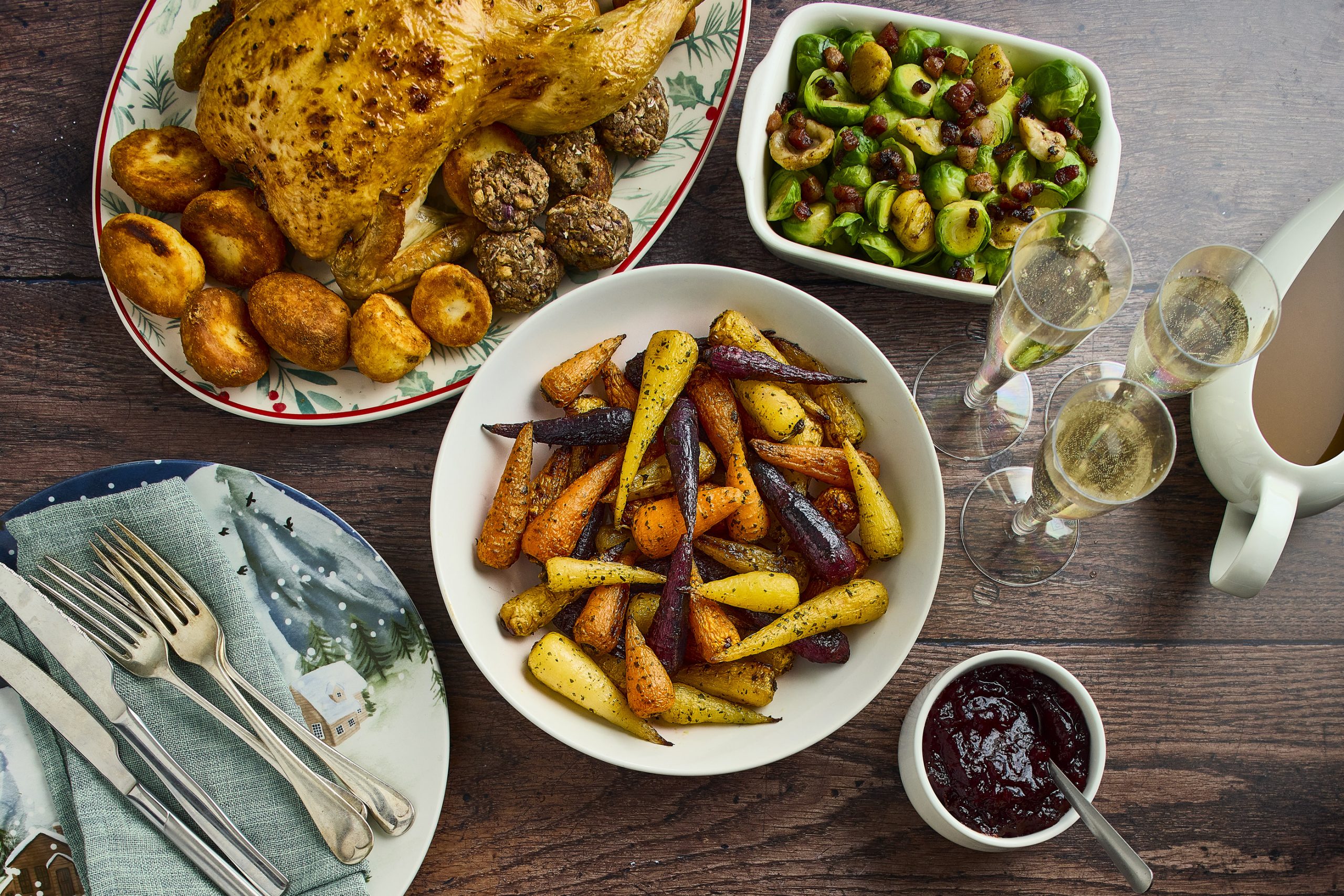 A bowl of rpasted veg, surrounded by the other pieces of a roast dinner on separate plates